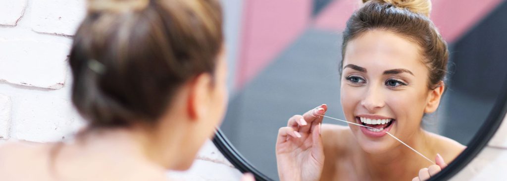 Woman Flossing in front of Mirror